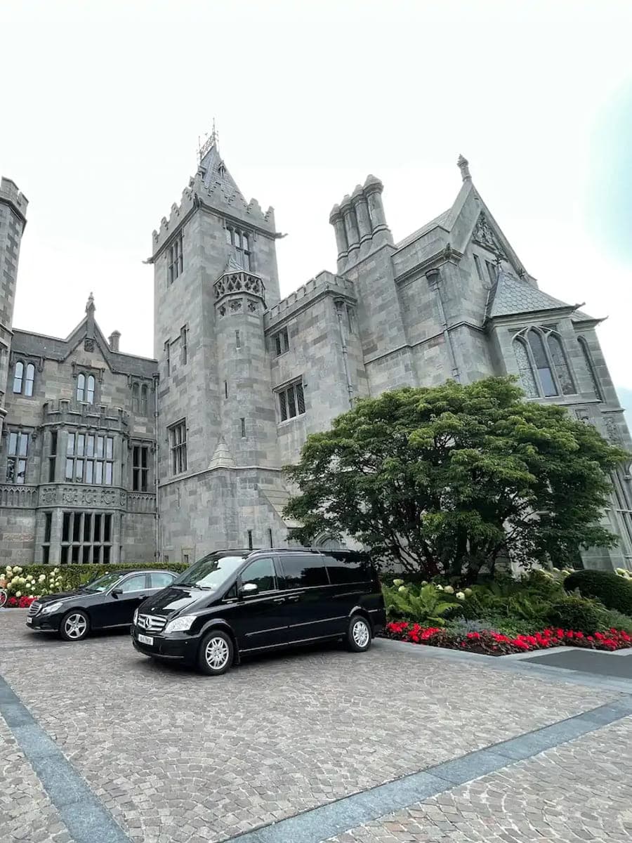 The neo-Gothic front of Adare Manor, County Limerick, with a car waiting at the entrance