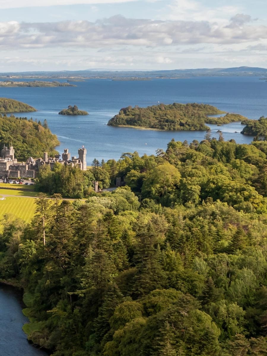 Ashford Castle above the wooded shore of Lough Corrib, County Mayo, seen from the air